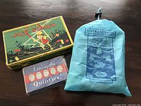 Three vintage games arranged side-by-side showing Magnetic Jack Straws box, Line Up the Quinties small box, and River Crossing bag