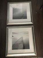 Pair of 23x23 inch matted framed prints shown flat on floor, one featuring a sailboat on calm water in black and white.