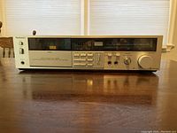 Front view of the Technics cassette player showing the front panel with buttons, display, headphone jack, and volume knob.