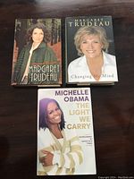 Three hardcover books on a wooden surface: two by Margaret Trudeau and one by Michelle Obama.