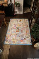 Full view of vintage patchwork quilt laid flat on wooden floor showing the full pattern and blue border.