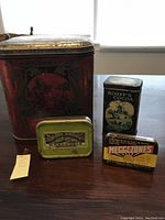 Photo showing all four vintage tins together on a table, highlighting their relative sizes and condition.