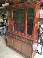 Front angle view of solid wood dining room display hutch showing glass doors and bronze hardware.