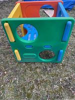 Side view of the Little Tikes gym box showing green panel with circular and small cutouts, and molded handles.