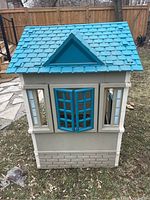 Front side showing blue peaked roof, large central window with blue opening shutters and side window panes.