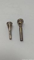Two trumpet mouthpieces standing upright showing full body and stem