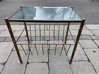 Front perspective of the square side table showing reflective glass top, brass frame, and vertical dividers of magazine rack.
