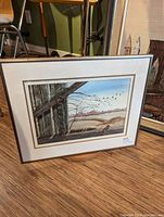 Framed watercolor painting of rustic barn interior with barbed wire and birds in flight over a rural field.