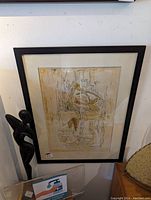 Framed abstract art print with beige and brown tones, dark brown frame, and glass covering.