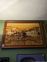 Frontal view of the signed original abstract cityscape painting with wooden frame hanging on green wall