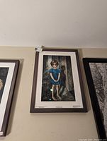 Framed Keane licensed serigraph print titled 'The First Grade' showing a barefoot young girl in a blue dress against a door background.