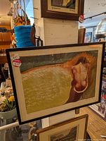 Photo of a framed limited edition serigraph with abstract organic shapes and earthy colors, displayed in an antique or vintage store setting with other art and decor visible.