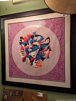 Photo of the framed theater style serigraph print showing an abstract, colorful design featuring geometric shapes and a stylized theatrical mask.