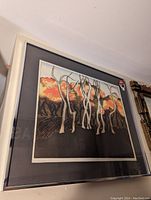 Framed artwork featuring abstract white tree figures set against an orange-red toned landscape background, housed in a cream-colored frame.