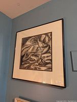 Framed black and white drawing hanging on a wall, showing an abstract design with various shapes and shading.