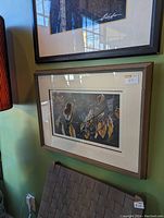 Photo of framed well known artist print hanging on wall with brown wooden frame and double mat. Print features people on horses illustration.