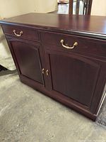 Front side view of cherry wood buffet showing drawers and double-door cabinets with brass handles.