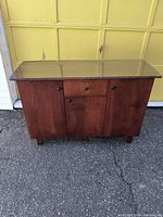 Front view of cherry wood buffet dining cabinet with glass top, showing drawer and two cupboards
