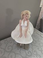 Marilyn Monroe Seven Year Itch doll standing on the base in white dress.