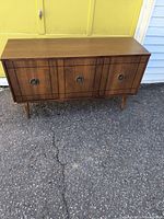 Full front view of the 1960s wooden record cabinet showing three closed doors and tapered legs.