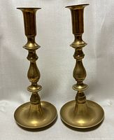 Front view of a pair of vintage brass candle holders, showing height and design details.