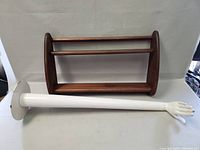 Pair of items showing the teak wall shelf and white metal plant stand lying on side