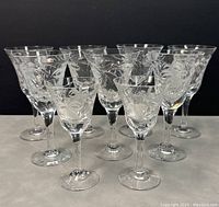 Nine Royal Brierley crystal glasses arranged in rows, showing etched floral patterns on clear glass in two different sizes.