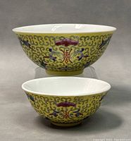 Front view of the two yellow famille jaune porcelain bowls, showing floral and cloud scroll designs and the relative sizes