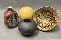 Four Italian decorative pottery items: yellow globe container, brown flower bud vase, small round vase, floral glazed bowl.