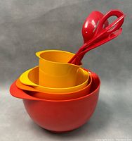 Front angle view of the nested mixing bowls and red utensils inside the smallest bowl, showing vibrant red and yellow colors in melamine material