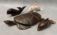 Set of four sea creature figurines: large wooden turtle, marble dolphin on clear stand, two small wooden whales