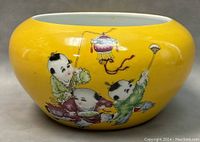 Front view of the large porcelain bowl showing three Chinese children playing against yellow background