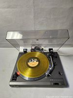 Front angled view of Sony PS-11 turntable with clear yellow record on aluminum platter and open dust cover