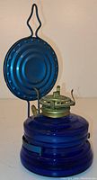 Front view of vintage cobalt blue glass oil lamp with metal reflector and green burner