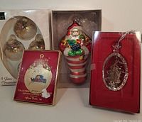 Four Christmas ornaments displayed: Dept 56 Santa stocking, 24k gold tone ornament, packaged vintage floral ball set, boxed Lenox crystal ornament visible.