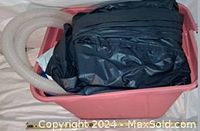 Photo of the folded inflatable pool and attached hoses stored in a plastic container