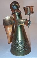 Full view of vintage brass and copper angel candle holder with etched floral patterns and attached wings, holding a candle socket.