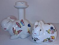 Photo showing both ceramic figures: the bunny rabbit cotton ball dispenser with floral designs and the rabbit candleholder decorated with butterflies.