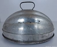 Closed ice cream mold with domed lid, showing metal handle on lid and sculpted scalloped design with signs of rust and wear.