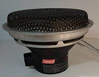 Side and angled view showing the black base of the heater with Coleman branding and control knob.