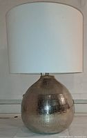 Full view of the moondrop shaped nickel iron table lamp with white drum shade.