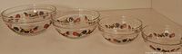 Five clear glass nesting bowls with colorful fruit pattern around the edges, arranged largest to smallest