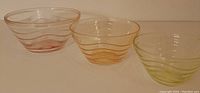 Three colorful glass nesting bowls with spiral colored stripes shown side by side.