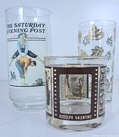 Three vintage glass tumblers arranged side by side on white surface showing the Hollywood film star designs and Saturday Evening Post cover