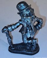 Front view of vintage pewter leprechaun figurine smiling and winking, with detailed outfit and hat showing shamrock.