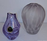 Two vases side by side against a white background: a small purple Bohemian Czech crystal vase with label and a larger lavender satin finish vase with textured blown mold pattern.