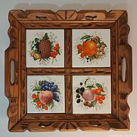 Top view of wooden serving tray with four ceramic tiles featuring painted fruit clusters.