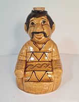 Front view of ceramic tequila decanter jug showing man figure with black painted hair, mustache, and traditional garment details.
