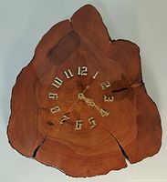 Front view of the wood slab clock showing the dial and natural wood grain with cracks and bark edges.