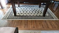 Full view of rectangular Persian rug under a wooden table on wood flooring, showing the overall design and size.